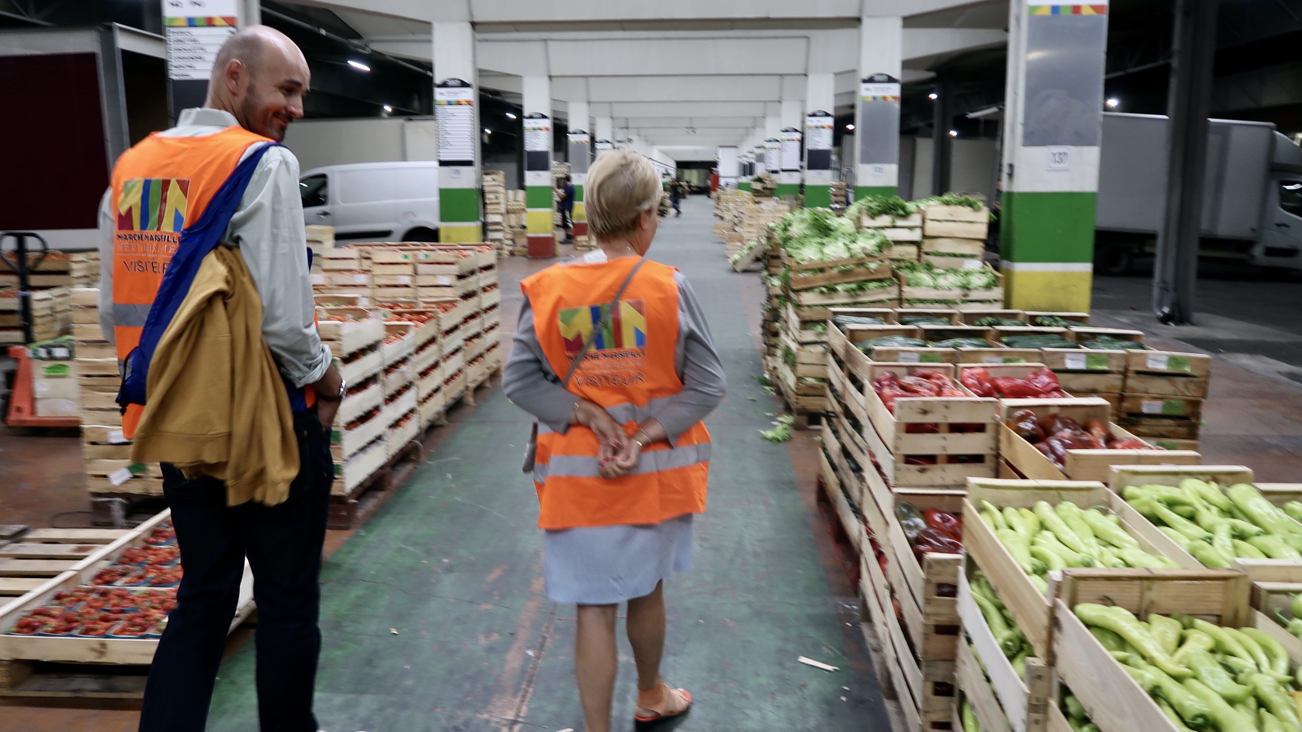 Notre guide Benjamin Potet et une visiteuse dans les allées des producteurs, au marché des Arnavaux. (Photo : CMB)