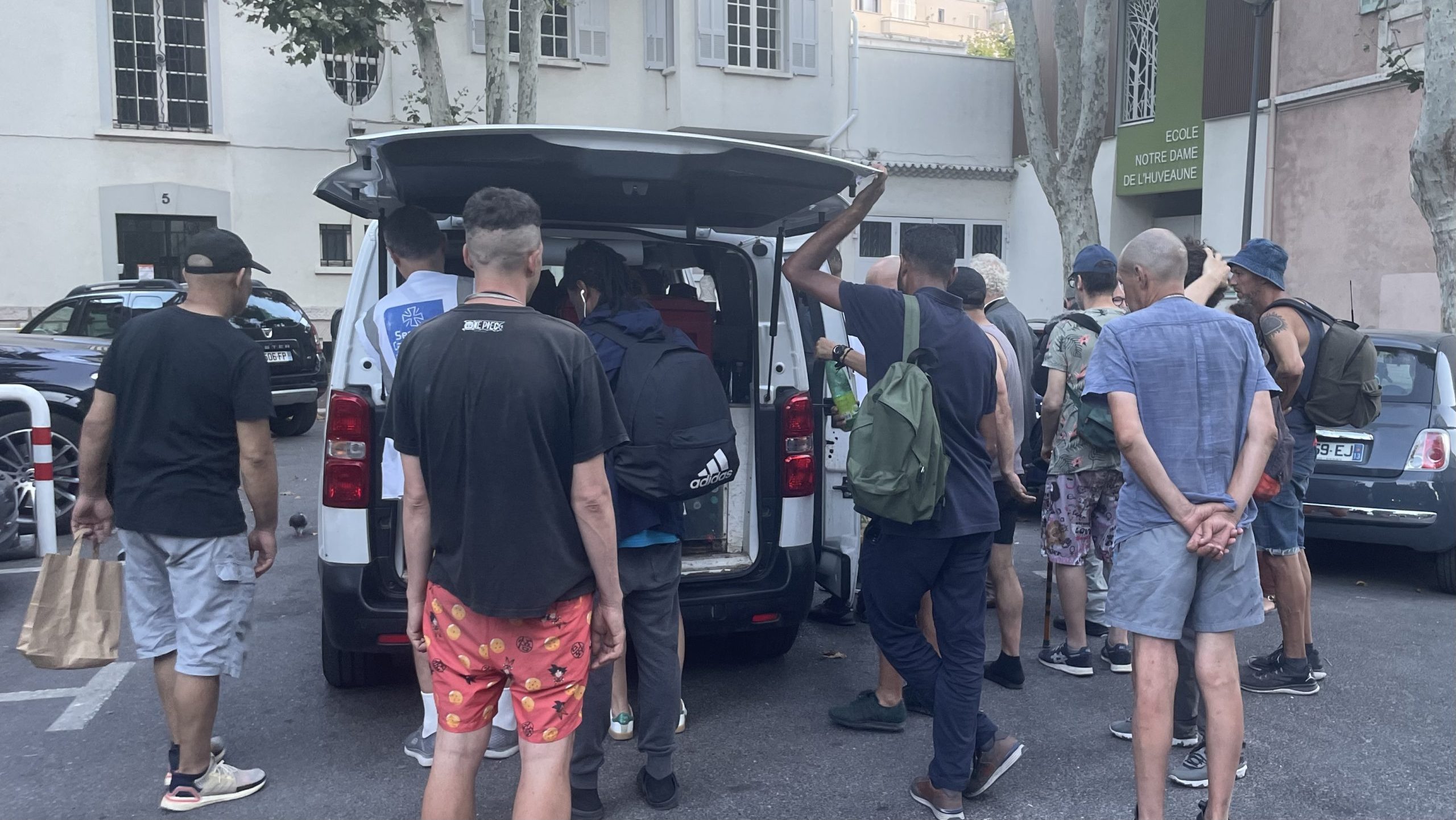 Une vingtaine de personnes attend une distribution d