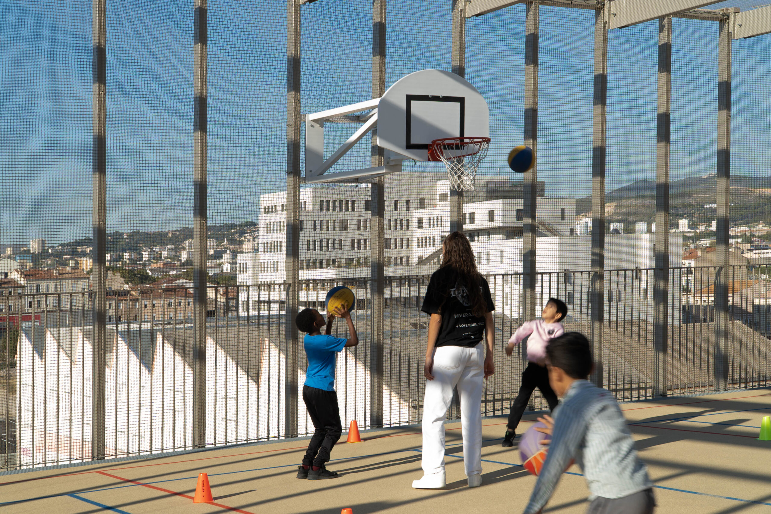 Des enfants du quartier jouent au basket sur le toit de l