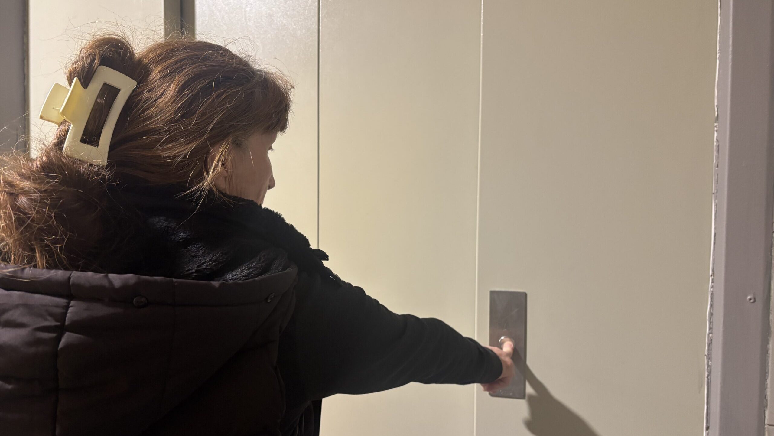 Corine appuie sur le bouton de l'un des ascenseurs en panne dans son immeuble depuis plusieurs mois. (Photo : AK)